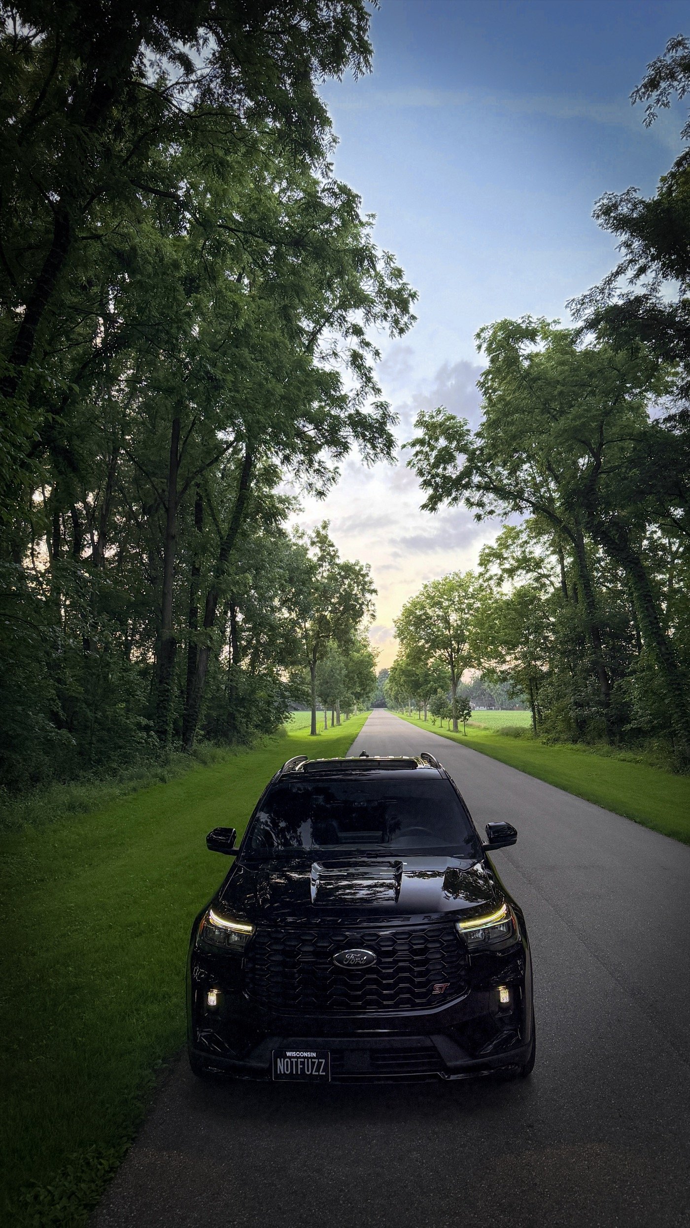 Black 2025 Ford Explorer ST on a tree-lined road